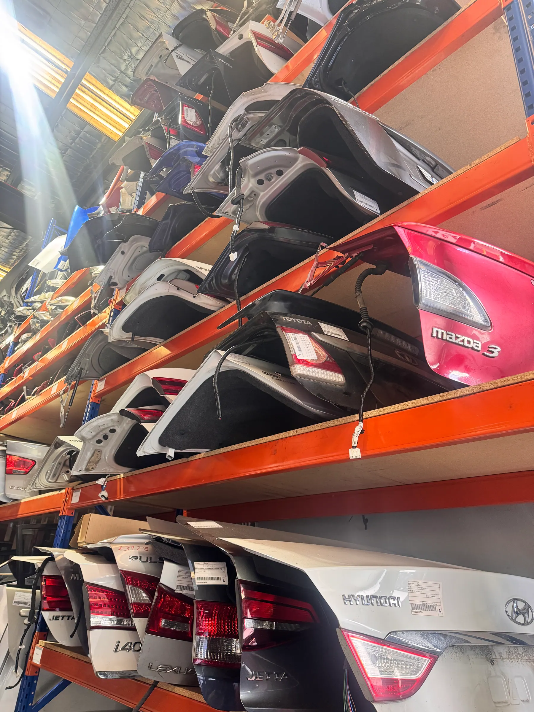 Rows of rear tailgates and panels stacked on warehouse racking.