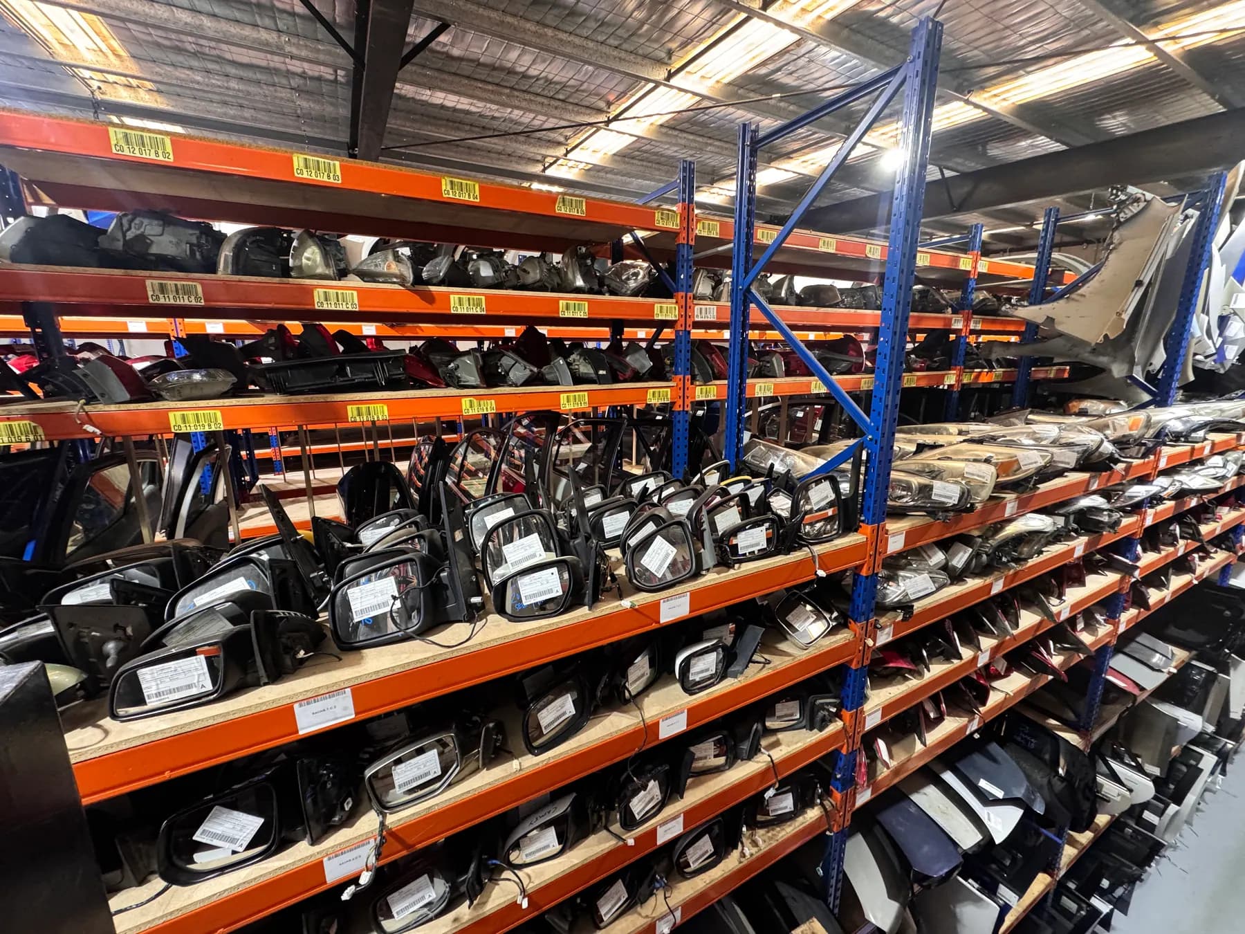 Wide warehouse view showing side mirrors and body parts in stock.